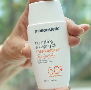 A hand holding a bottle of the Mesoetetic nourishing antiaging oil with spf 50 to help increase skin collagen and skin elasticity