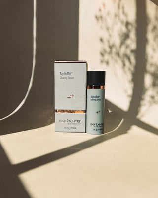 Tan background with a box and bottle of the Alpharet clearing Serum that helps to rejuvenate and clarify the appearance of oilier, blemish-prone skin.