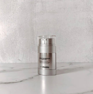 Jan Marini Age Intervention Duality bottle that helps control acne and aging skin sitting on marble table with gray background.